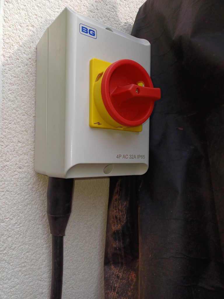 Red and yellow rotary isolator switch fixed to an outside wall