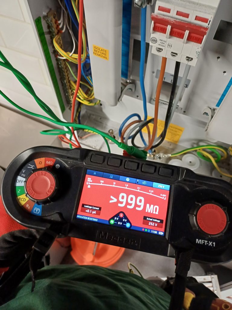 Multifunction tester showing an insulation resistance reading above 999 megohms at a distribution board